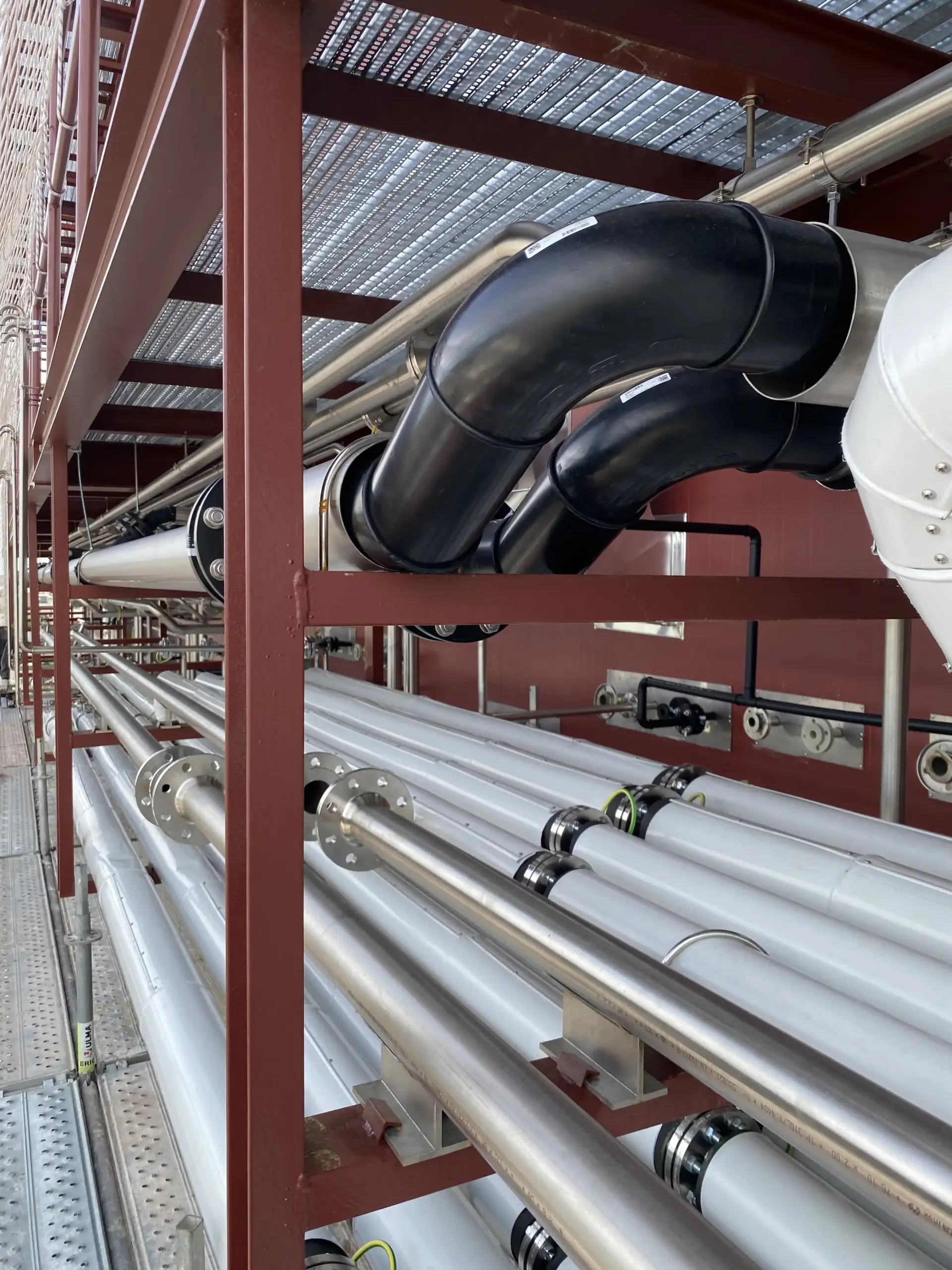 Interconexión de tuberías industriales de acero y polietileno instaladas en una pasarela técnica exterior, con soportes metálicos y uniones bridadas preparada por Soldaduras Dad, expertos en sistemas de fluidos industriales en Zaragoza