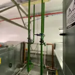 Líneas de proceso industriales verticales conectadas a maquinaria en sala técnica por Soldaduras Dad, empresa especializada en sistemas de fluidos industriales