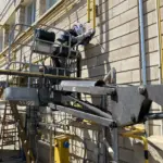 Trabajos de soldadura en tubería de gas instalada en fachada industrial, realizados con plataforma elevadora y medidas de seguridad en altura por Soldaduras DAD, expertos en soldadura industrial